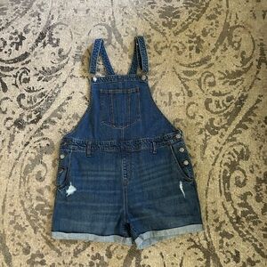 Blue denim overalls with button fly and raw hem
